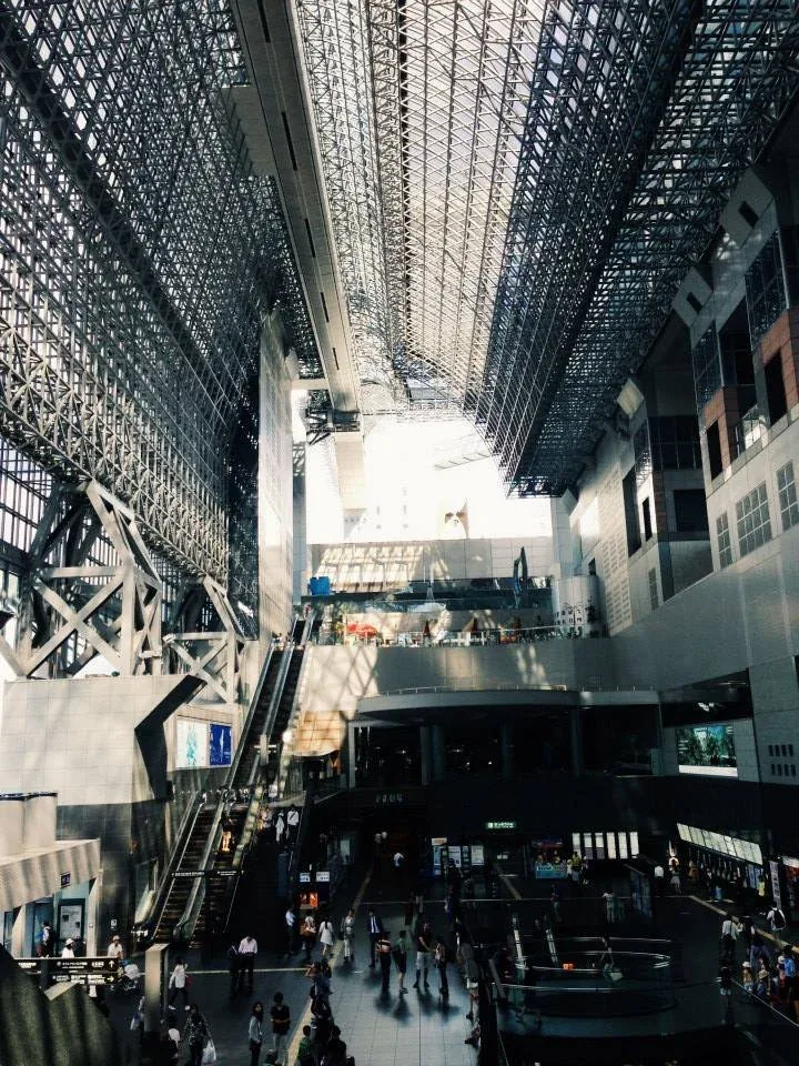 Vast steel-latticed station atrium with escalators and crowds below