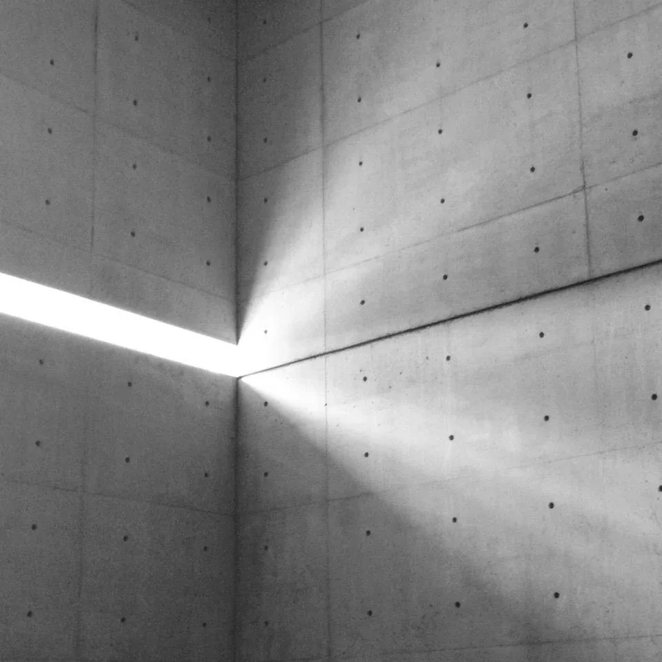 Beam of light cutting across a concrete corner marked with tie holes
