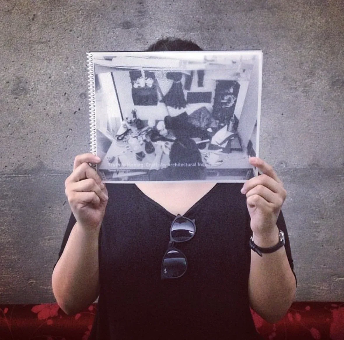 Person holding a spiral-bound architecture book in front of their face